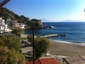 uma vista para uma praia com um barco na água em Melissa Rooms em Agios Kirykos