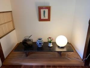 a table with two vases and a lamp on it at Private GUEST HOUSE KUMANOYASA in Tanabe