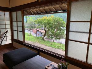 Private GUEST HOUSE KUMANOYASA في تانابا: غرفة بها نافذة تطل على شجرة