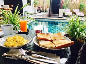 a breakfast table with toast and scrambled eggs and juice at Samui Star Guesthouse in Chaweng