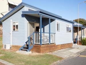 
a white and blue house with a blue door at Horseshoe Bay Holiday Park in South West Rocks
