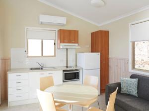 a kitchen and dining room with a table and a couch at Horseshoe Bay Holiday Park in South West Rocks