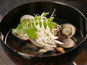 a black bowl of soup with vegetables and noodles at Shouheikaku in Matsue