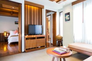 a living room with a television and a bed at Maehaad Bay Resort - SHA Plus in Mae Haad