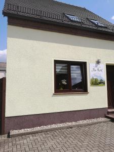 ein weißes Gebäude mit einem Fenster mit einem Schild darauf in der Unterkunft Ferienhaus Am Park in Löbnitz