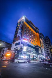 un grand bâtiment avec des voitures garées devant lui dans l'établissement Hotel Noblesse, à Séoul