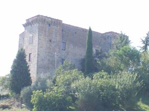 un gran edificio de ladrillo con árboles delante de él en Agriturismo Castello Di Belforte, en Todi
