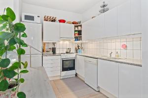 a white kitchen with white appliances and a plant at rækkehus ved amagerstrand in Copenhagen