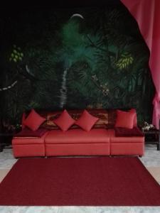 a red couch with red pillows on a red rug at Toni Arts Villa in Nabas