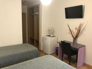a room with two beds and a desk and a television at Pension Berceo in Logroño