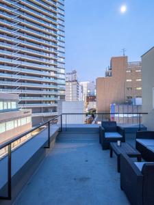 nid OSAKA Atre Nakatsu في أوساكا: شرفة مع مقاعد ومبنى كبير