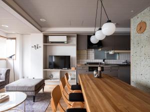 nid OSAKA Atre Nakatsu في أوساكا: مطبخ وغرفة معيشة مع طاولة وكراسي خشبية