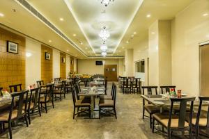 a restaurant with tables and chairs in a room at Quality Inn Ramachandra in Visakhapatnam