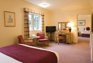 a hotel room with two beds and a television at Orton Hall Hotel & Spa in Peterborough