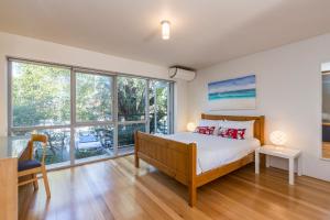 a bedroom with a bed and large windows at Cottesloe Tree Top Studio in Perth