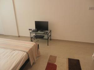 a bedroom with a bed and a tv on a table at Studio, E104 with double bed, kitchen & shower room, sunny balcony in Peyia