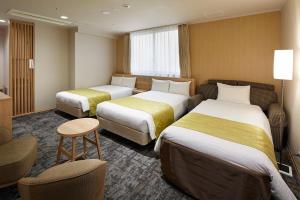 a hotel room with two beds and a table and chairs at Hotel Hokke Club Kyoto in Kyoto