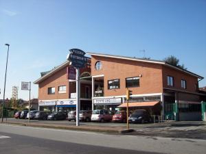 un gran edificio de ladrillo con coches estacionados frente a él en Abba Camere, en Borgaro Torinese