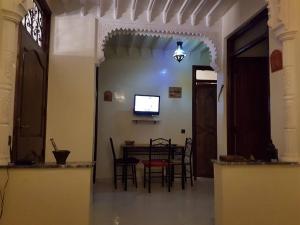 uma sala de jantar com mesa e cadeiras e uma televisão em Zwina Appart: A Small, Cozy Family Nest em Marrakech