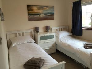 a bedroom with two beds and a dresser at New Forest Brockenhurst in Brockenhurst
