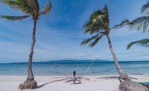 a girl on a swing between two palm trees on a beach at Cocohut Beach Resort Koh Phangan in Haad Rin