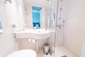 y baño blanco con lavabo y ducha. en Forenom Aparthotel Helsinki Kamppi - contactless check-in, en Helsinki