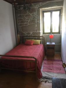 a bedroom with a bed with a red bedspread and a window at Casa Glória in Ribeiradio