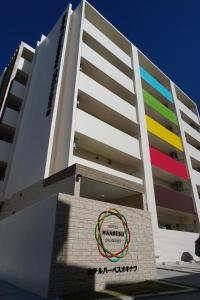 a multicolored building with a sign in front of it at Hotel Haabesu Okinawa in Urasoe