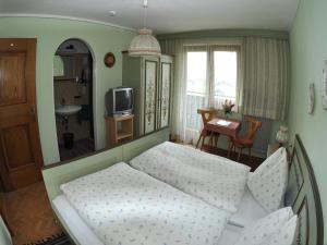 a small bedroom with a bed and a television at Pension Stubachblick in Uttendorf