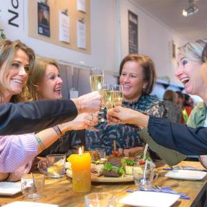 un grupo de mujeres sentadas alrededor de una mesa bebiendo vino en Milk and cookies, en Venlo
