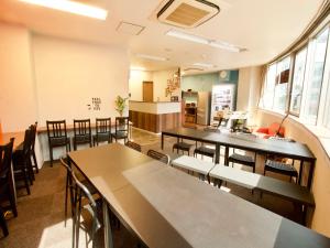 Osaka Guesthouse Nest في أوساكا: غرفة بها طاولات وكراسي ومطبخ