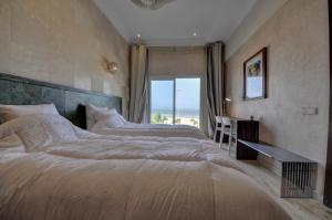 a bedroom with two beds and a desk and a window at Résidence Beach Mogador, Appartement n°29 in Essaouira