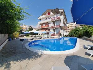 un hôtel avec une piscine en face d'un bâtiment dans l'établissement Hotel Alexander, à Giardini Naxos