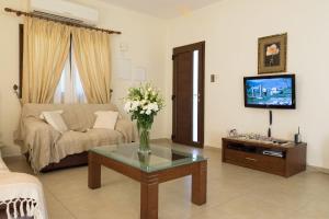 a living room with a couch and a table with flowers on it at Villa Tsikkos Tria in Polis Chrysochous