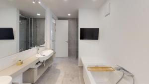 een witte badkamer met een wastafel en een bad bij Lieblingsplatz Neusiedl Appartement - Entspann dich in Neusiedl am See