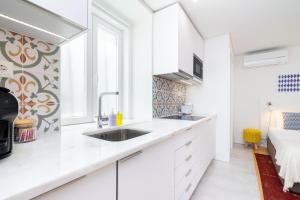 uma cozinha com armários brancos e um lavatório em Porta do Mar Deluxe Central Apartments em Lisboa