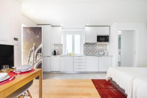 a white bedroom with a bed and a desk and a kitchen at Porta do Mar Deluxe Central Apartments in Lisbon