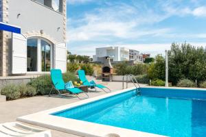 a pool with chairs and a table next to a house at Villa Patricia in Rogoznica