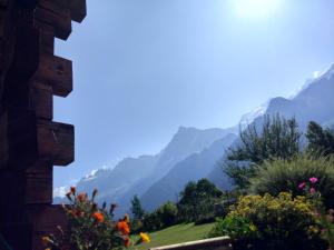 a view of mountains from a house with flowers at Chalet Le Marmouzet in Les Houches