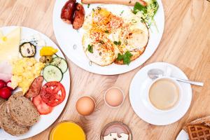 two plates of breakfast food on a wooden table at Apart Neptun in Gdańsk