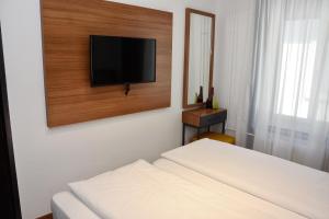 Schlafzimmer mit einem Bett und einem Flachbild-TV an der Wand in der Unterkunft Comfort Apartments by Livingdowntown in Zürich