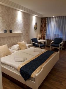 a bedroom with a large bed and two chairs at Hotel Eleon in Bad Teinach-Zavelstein