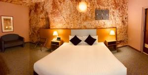 a hotel room with a large bed and two lamps at Desert Cave Hotel in Coober Pedy