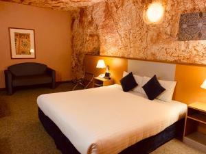 una camera d'albergo con letto e sedia di Desert Cave Hotel a Coober Pedy