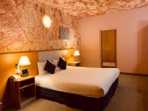 a hotel room with a bed and a telephone at Desert Cave Hotel in Coober Pedy