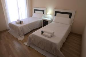 two beds in a room with white sheets at Apartamento Puente Romano Portal 4 1-B in Salamanca