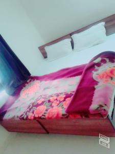 a bed with a red bedspread with flowers on it at Roj Cottage in Mount Ābu
