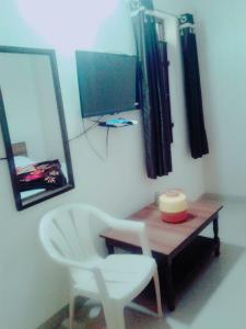 a room with a table and a chair and a television at Roj Cottage in Mount Ābu