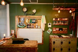 a coffee shop with a clock on a green wall at Greenwood Hostel in Izumi-Sano