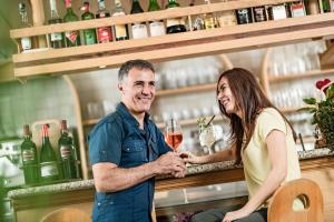 a man and woman standing at a bar with a glass of wine at Hotel Heide Park in Auer